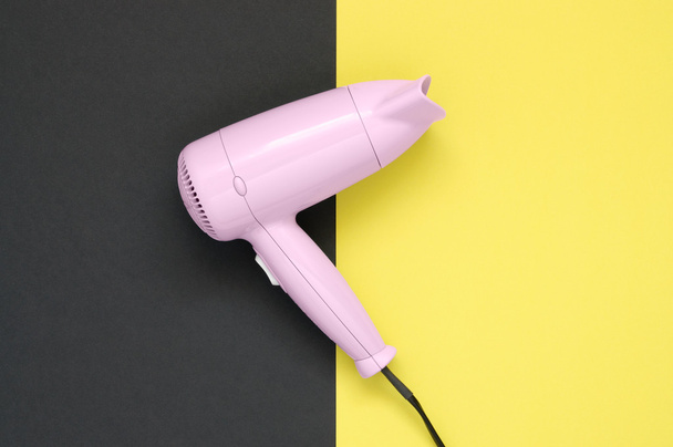 Pink hair dryer on black and yellow background - Photo, Image