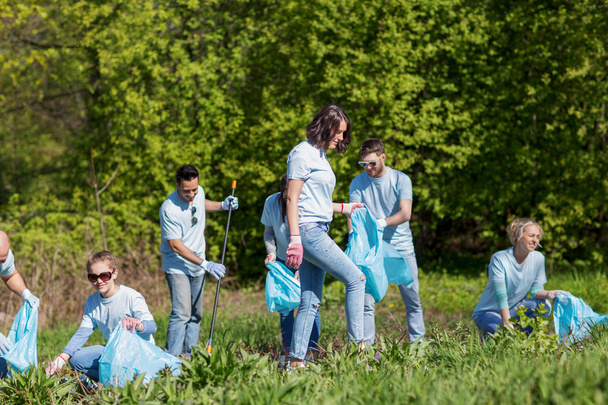 volunteers with garbage bags cleaning park area - Фото, изображение