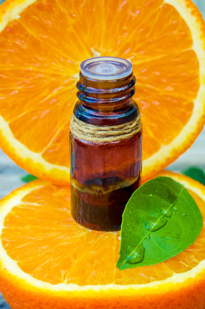 Fles oranje etherische olie voor aromatherapie (extract, tinctuur, afkooksel, SAP) geneeskrachtige eigenschappen van Orange. - Foto, afbeelding