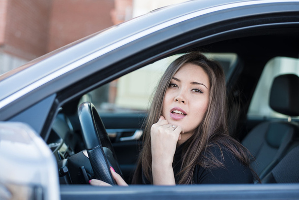  brunette woman with hand on chin in car  - Φωτογραφία, εικόνα