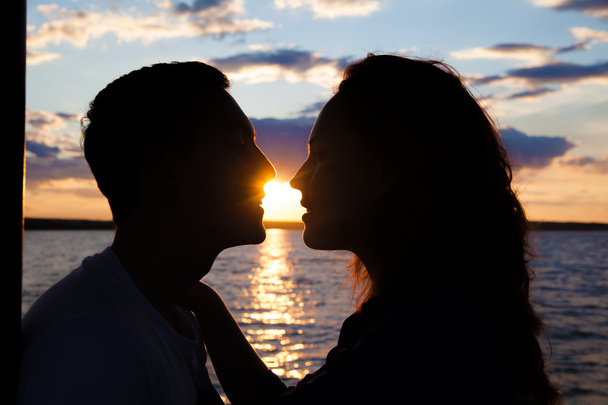 Silhouette of kissing couple over sunset beach background.  - Фото, зображення