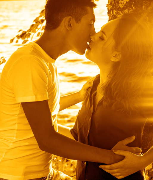 Ρομαντικό ζευγάρι ευτυχισμένο αγκάλιασμα και το φίλημα στην ηλιόλουστη παραλία.  - Φωτογραφία, εικόνα