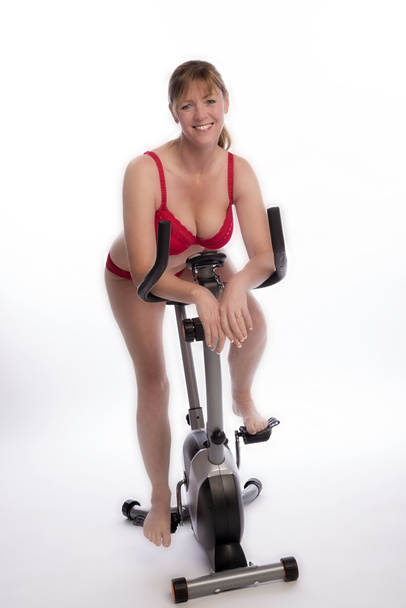 Γυναίκα που φοράει κόκκινα εσώρουχα ιππασίας ένα ποδήλατο γυμναστικής  - Φωτογραφία, εικόνα