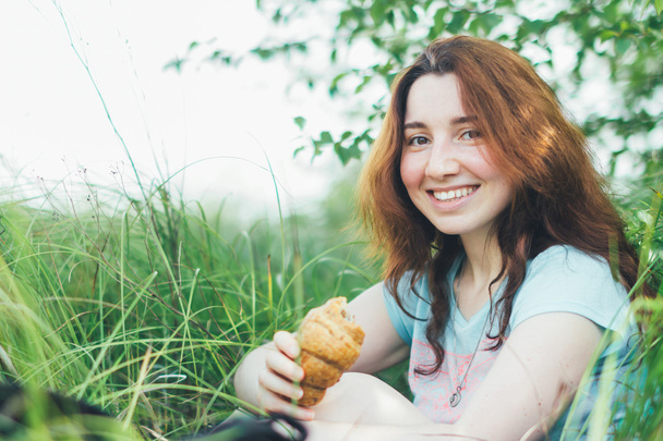 sonriente hermosa chica comer croissant
  - Foto, Imagen