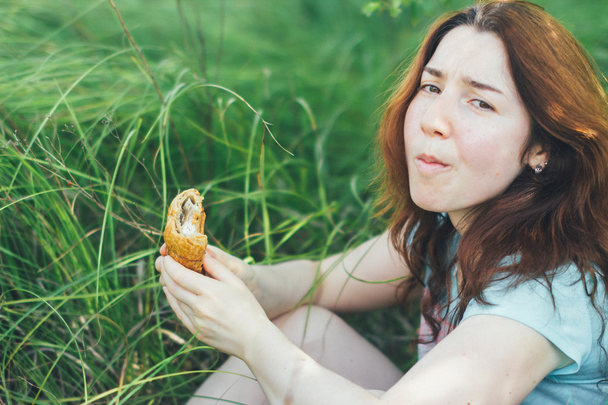 unhappy beautiful girl looks east eating croissant - Photo, Image