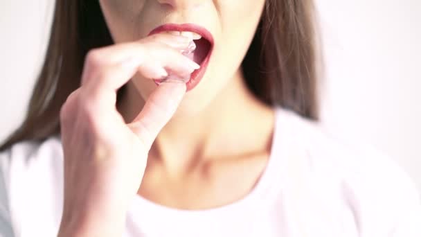 Close up of woman biting ice cube on beige background - Кадри, відео