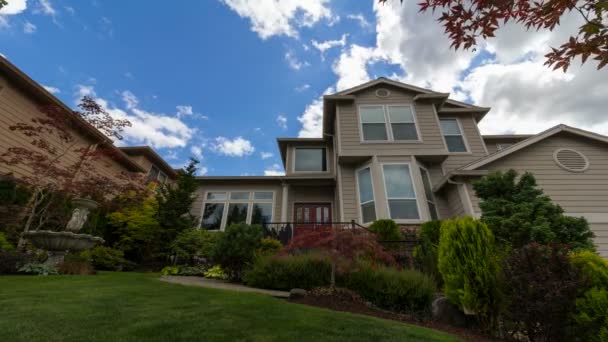 UHD time lapse of moving clouds and blue sky over suburb real estate house with manicured lawn and garden with Japanese maple trees and shrubs on a partly sunny day - Footage, Video