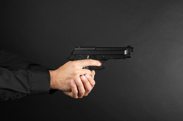 Man's hands holding gun  - Фото, изображение