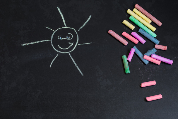 colored chalks, black blackboard with drawings of the sun - Photo, Image