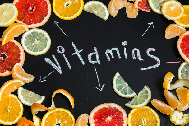 the word vitamins with citrus fruit written on black board - Photo, Image