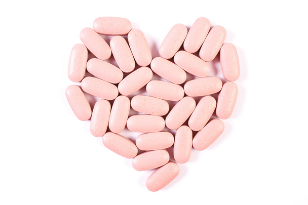 Heart shaped medical pills and capsules on white background, health care concept - 写真・画像