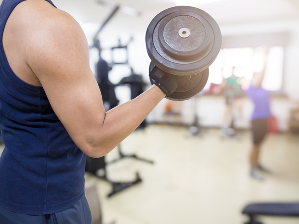 Closeup of a young athlete man lifting weights at sport club - Photo, image