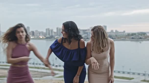 drei junge Frauen in Partykleidern haben Spaß und posieren für Fotos vor der Skyline - Filmmaterial, Video