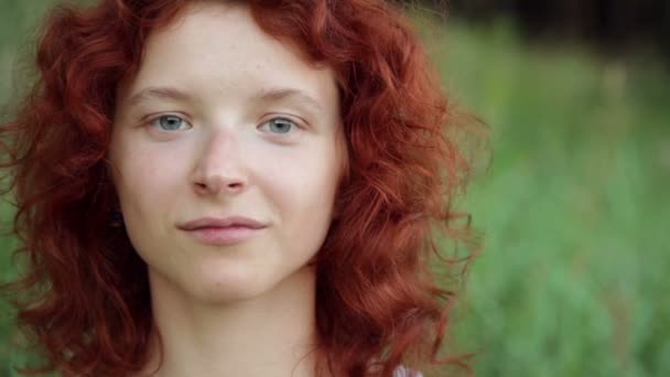 Kobieta w okulary uśmiechający się przeciwko zielona trawa - Materiał filmowy, wideo