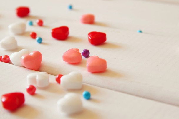 Red, pink and white hearts shape candies on wooden table - Foto, Imagen