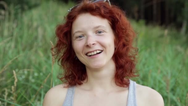 Kobieta w okulary uśmiechający się przeciwko zielona trawa - Materiał filmowy, wideo