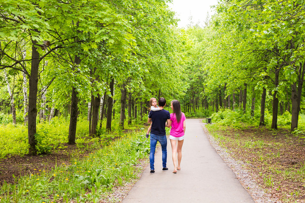 Onnellinen nuori perhe kävelee vihreässä luonnossa
. - Valokuva, kuva