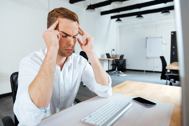 Stressato giovane uomo d'affari che ha mal di testa in ufficio
 - Foto, immagini