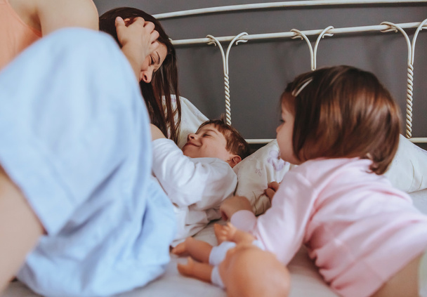 Uvolněná matka a synové si hrají nad postelí - Fotografie, Obrázek