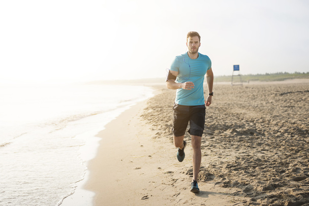 Jóképű férfi fut a strandon  - Fotó, kép