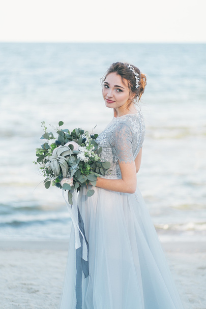 Πανέμορφη νύφη με Γαμήλια ανθοδέσμη από τη θάλασσα - Φωτογραφία, εικόνα