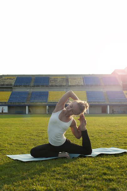 Blonde woman doing yoga exercises outdoors. - Foto, afbeelding