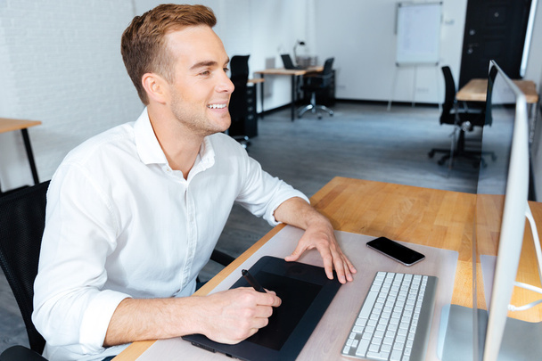 Happy male designer using computer and graphic tablet in office - Photo, image