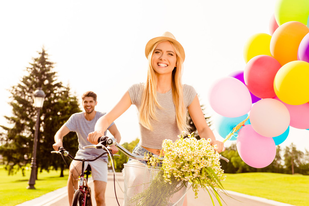 Pretty smiling girl riding bicycle with her boyfriend - 写真・画像