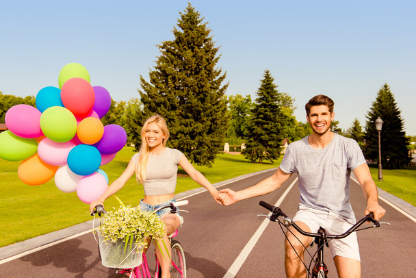 Happy young lovely couple in love cycling and holding hands - Foto, Imagen