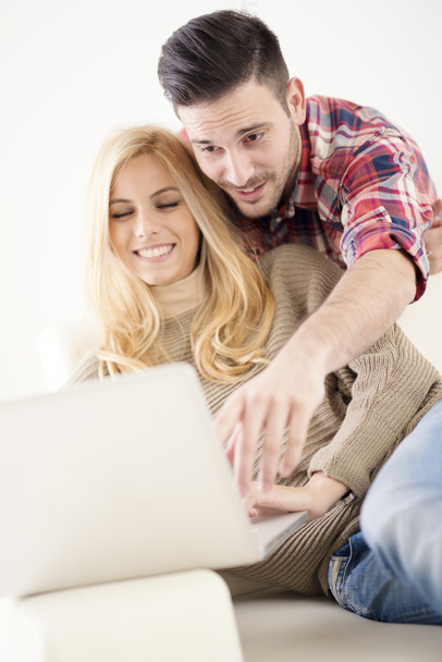 Evde, dizüstü bilgisayar kullanarak ve gülümseyen tarama internet genç Çift  - Fotoğraf, Görsel