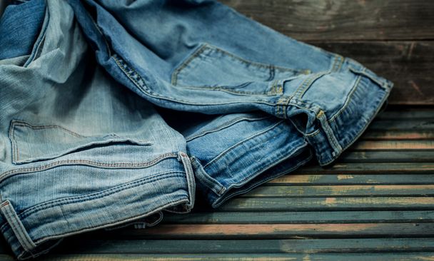 bunch of jeans on a wooden background strewn, fashionable clothes - Photo, Image