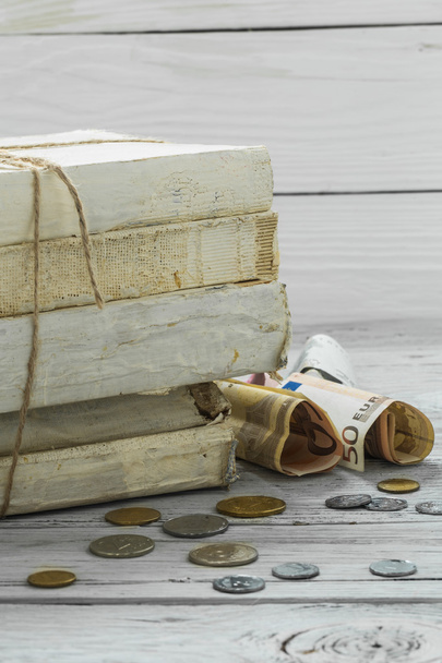viejos libros blancos con dinero y monedas sobre fondo de madera
 - Foto, Imagen