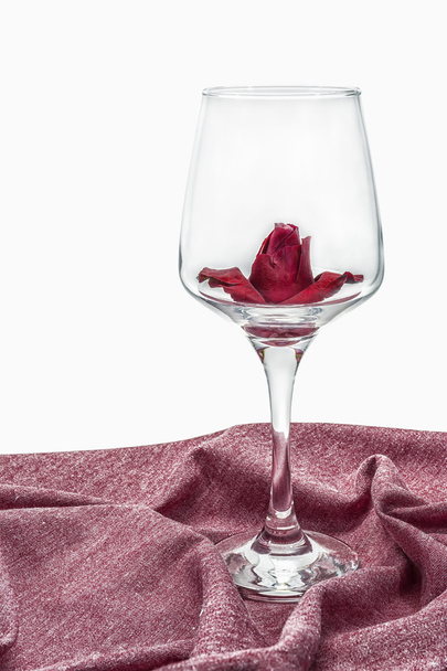Rosas rojas en un vaso sobre un paño rojo aislado sobre fondo blanco
. - Foto, Imagen