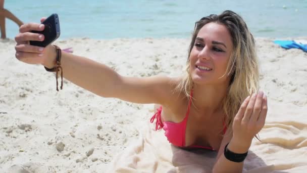 žena v růžové bikiny dělá selfie na pláži - Záběry, video