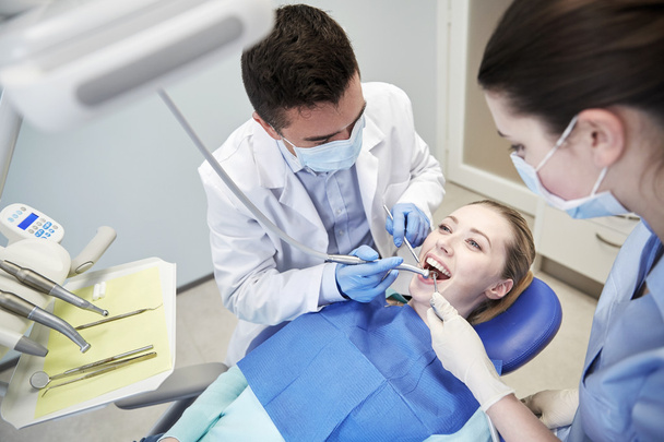 male dentist treating female patient teeth - Foto, Bild