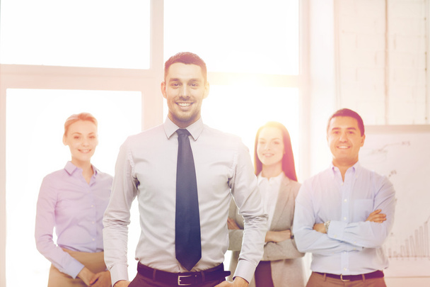 smiling businessman in office with team on back - Photo, image