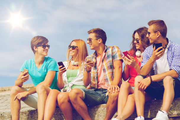 group of smiling friends with smartphones outdoors - Фото, зображення