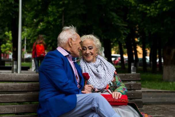 Oude man en de oude vrouw praten op een bankje. - Foto, afbeelding