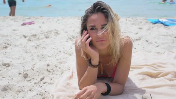 cheerful girl in pink bikini uses smartphone on the beach - Footage, Video