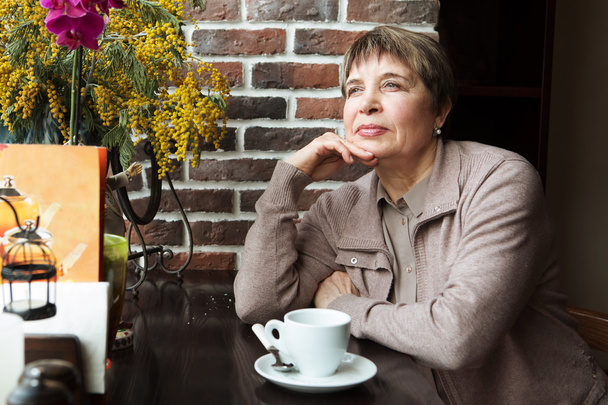 Portrait of senior woman in smart clothes having tea in cafe - Foto, imagen