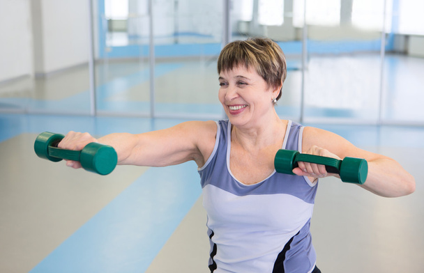 Portrait of pretty senior woman exercising with dumbbells - Foto, Imagem