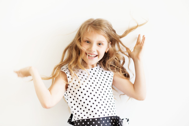 Lovely frisky little girl in a polka-dot dress against a white b - 写真・画像