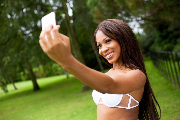 young woman in the park taking a selfie in her bikini - Fotoğraf, Görsel