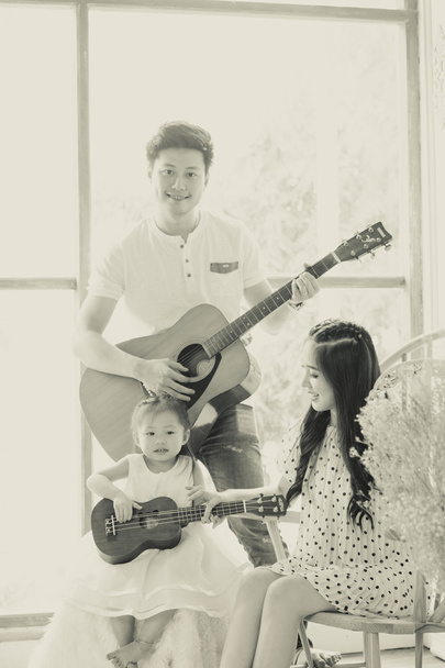 Familie musiceren thuis met gitaar, vader moeder en dochter - Foto, afbeelding
