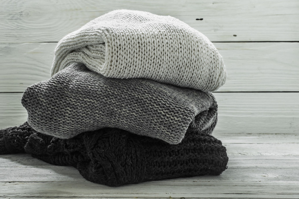暖かいニットセーター、木製の背景に3枚、黒、灰色、白 - 写真・画像