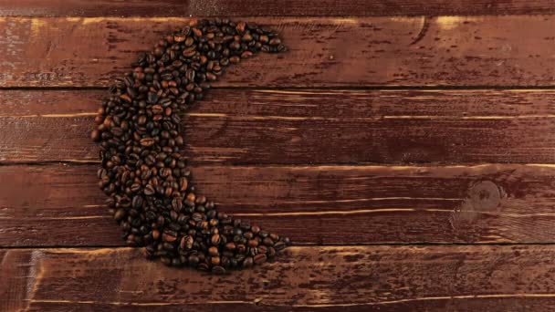 Young man puts a cup of coffee beside roasted black coffee beans arranged in a moon shape on dark background. Coffee beans in moon shape - Ramadan food concept - Footage, Video