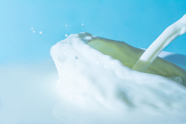 Splashes of milk on the surface of the milk on a light blue background - Fotoğraf, Görsel
