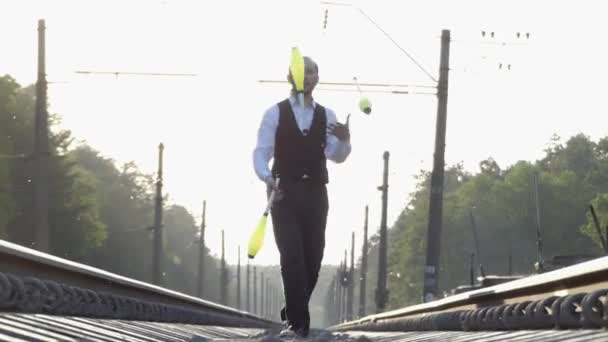 Ο τύπος Juggling για το τρένο κομμάτια. Αργή κίνηση. Ηλιοβασίλεμα. Εξισορρόπηση επί της σιδηροδρομικής γραμμής. - Πλάνα, βίντεο