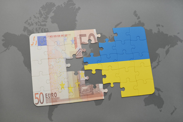 головоломка с национальным флагом Украины и банкнотой евро на фоне карты мира
. - Фото, изображение