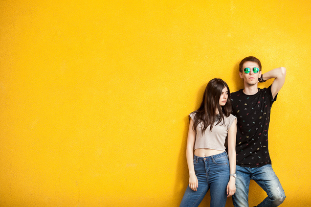 Couple in fashion posing on yellow wall - Фото, зображення
